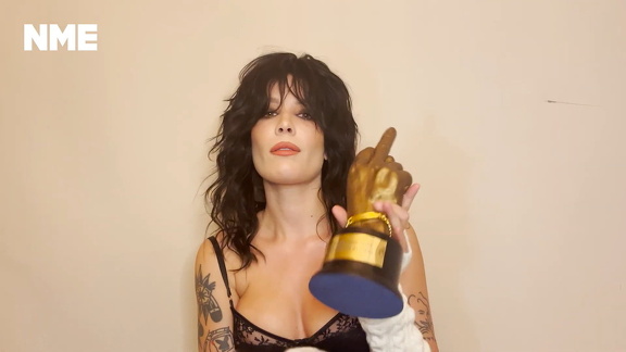 Halsey shows cleavage in a bra while holding her award